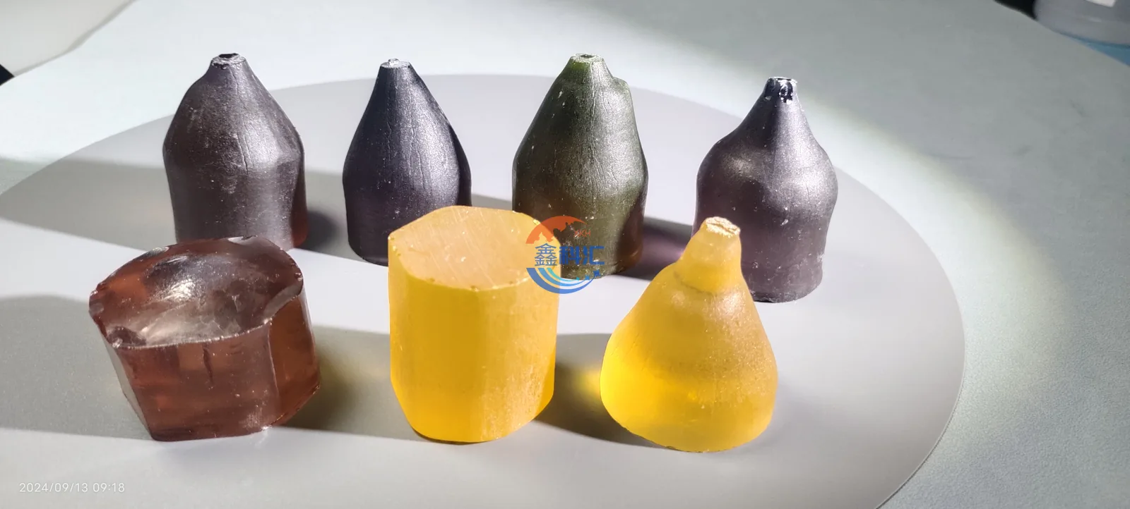 Xinkehui yellow and purple YAG single crystal boules arranged on a white surface
